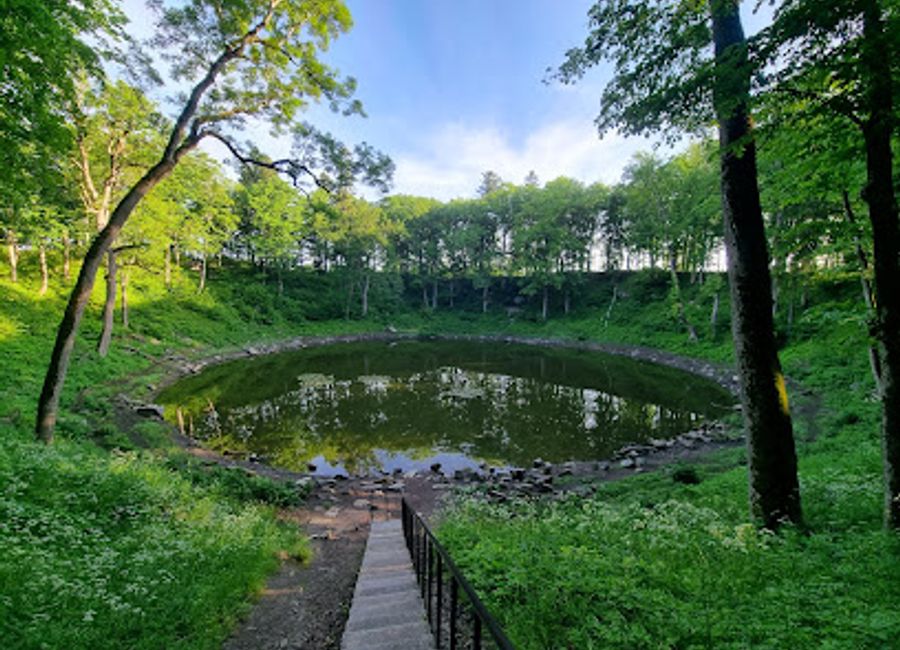 Explore the enchanting beauty of Kaali Kraater, Estonia's largest meteorite impact site, surrounded by lush landscapes and rich geological history.