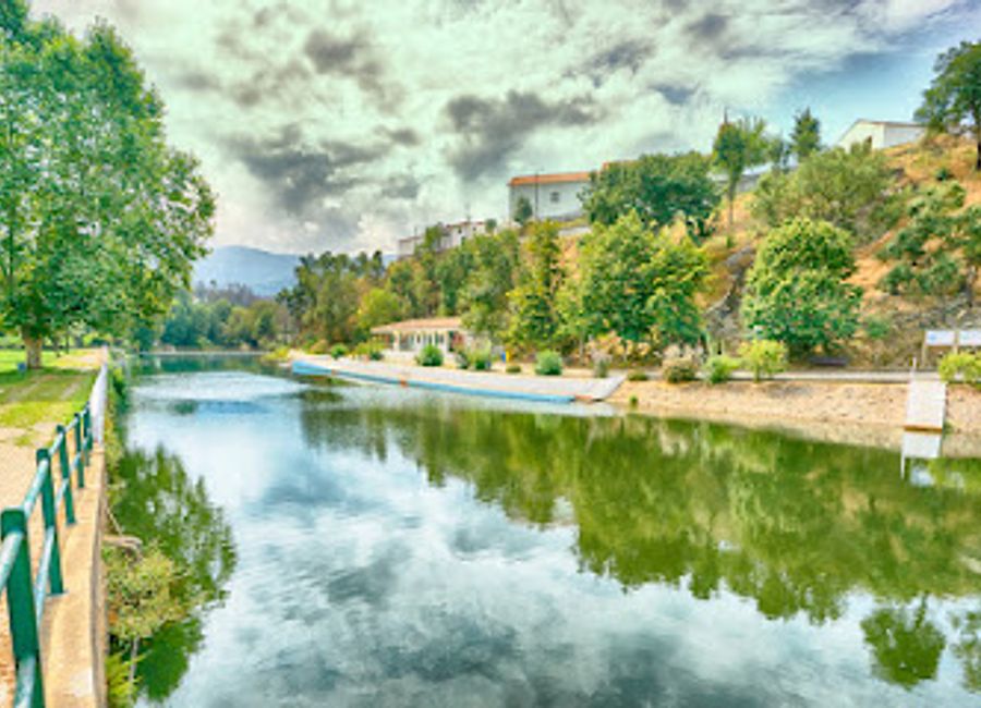Experience the serene charm of Praia Fluvial da Senhora da Graça, a stunning lake shore swimming area in Serpins, Portugal, perfect for relaxation and adventure.